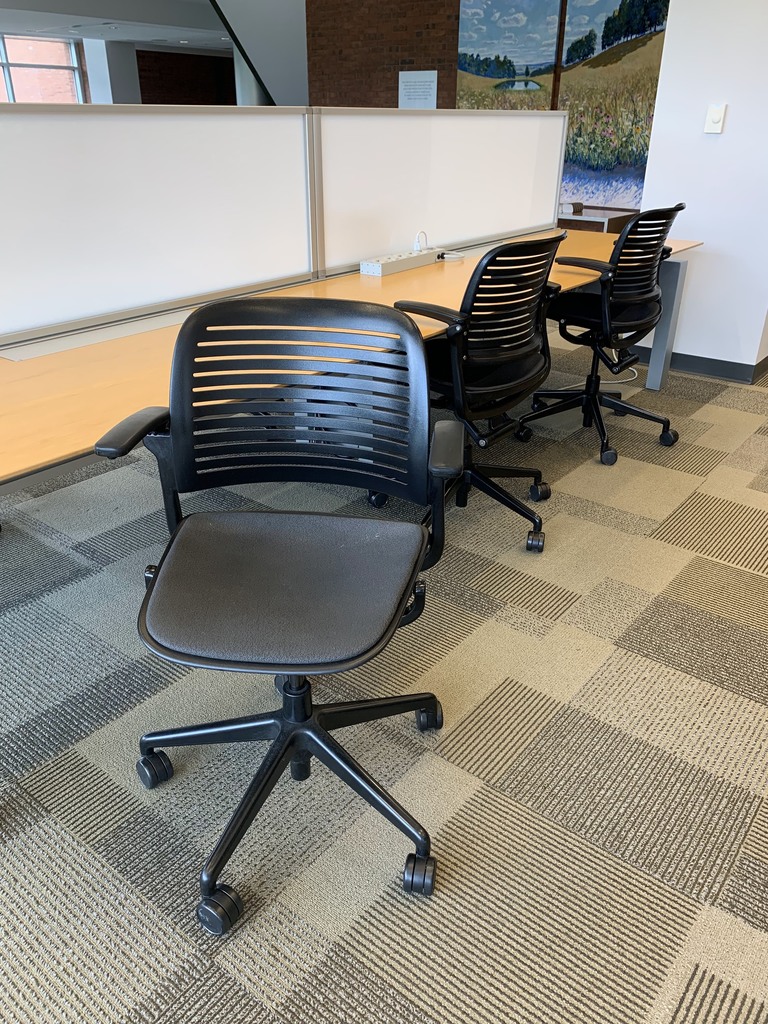 Black rolling chairs with arm rests, vented plastic backs, and thin foam seat cushions