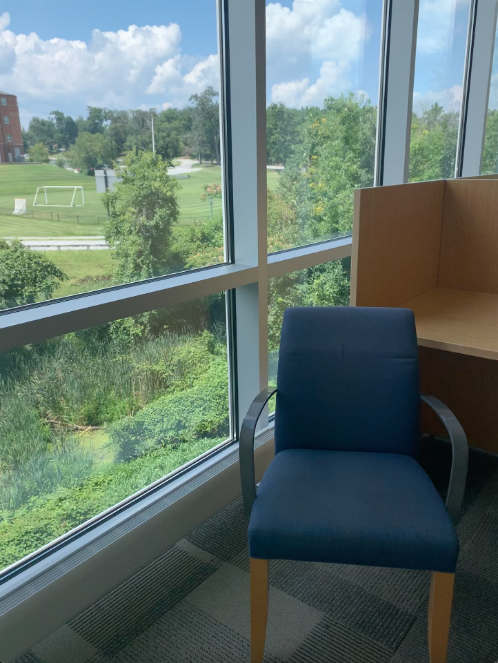 Stationary arm chair with blue upholstery in front of a study carrol, by a window